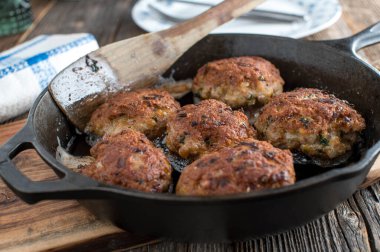 Fried meatballs in a cast iron pan on wooden background