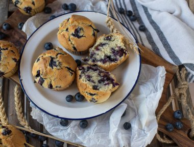 Fresh baked blueberry muffins on a rustic enamel plate on wooden background