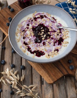 Delicious natural and healthy breakfast bowl with yogurt, blueberry compote and oats. Served on rustic and wooden background. Top view with copy space