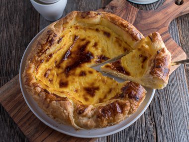 Puff pastry tart with cheesecake filling. Served isolated on wooden table background