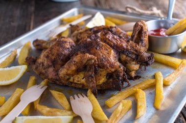 Homemade fresh cooked crispy whole roast chicken with fresh french fries. Served ready to eat on a baking tray