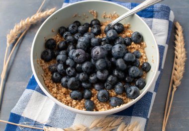 Breakfast cereal porridge with oats, amaranth and quinoa. Topped with fresh blueberries