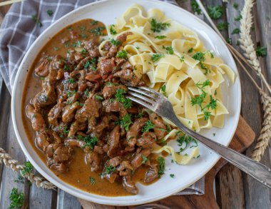 Shredded chicken with cream sauce and tagliatelle noodles on a plate with fork. 