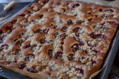 Fruit cake on a baking tray. Fresh and homemade plum cake with crumble