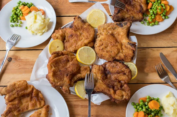 Family dinner table with breaded cutlets, mashed potatoes and vegetables