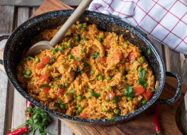 Ahşap masa üzerinde izole edilmiş kaşıkla, kırsal bir tencerede etli Sırp pirinci. Üst görünüm