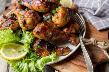 Tahta kesme tahtasının üzerinde tavuk budu olan tabak.