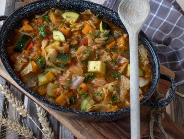 Ahşap arka planda kırsal bir tencerede lahana ile sebze çorbası.