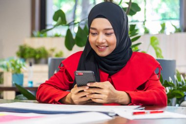 Girişimci Müslüman kadın iş ve eğitim için çevrimiçi müşterilerin siparişlerini kontrol etmek için cep telefonu kullanıyor