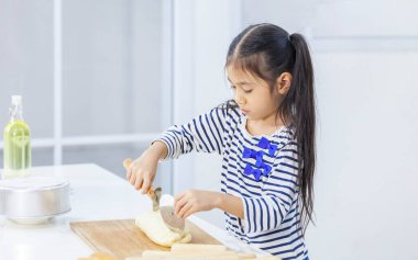 Genç Asyalı kız hamur yoğurup hamuru keserek modern mutfakta fotokopi alanı ile pişirme ve pişirme konsepti yapıyor.