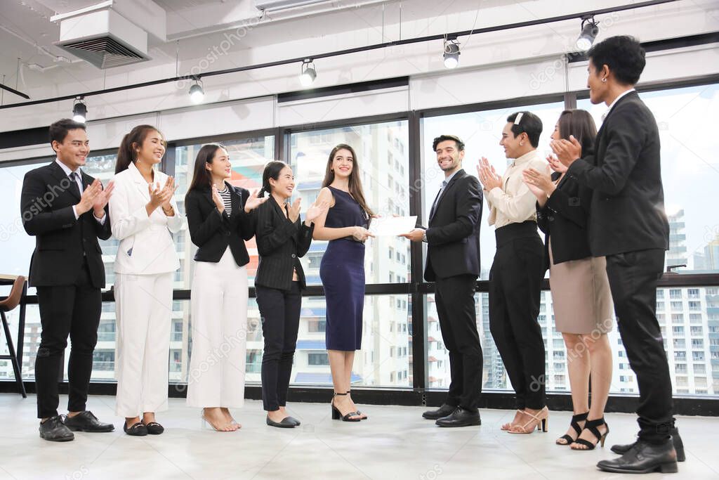 Group of diversity business corporation celebrating together in the meeting room with CEO given certificate to the branch manager while the rest of employee are cheerfully applauding