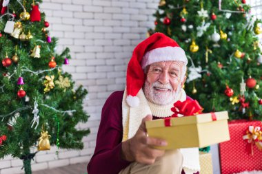 Kafkasyalı kıdemli adam Noel 'i mutluluk ve heyecan içinde kutlarken huzurevinde Noel ağacıyla hediyesini tutuyor.