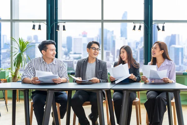 Genç Asyalı girişimci takımının, iş kurma ve eğitim için gökdelen görünümlü yeni proje pazarlama ve satış yönetimi için küçük bir takım toplantısı var