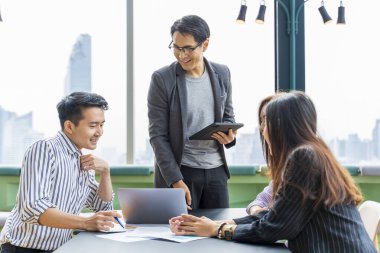 Genç Asyalı girişimci takımının, iş kurma ve eğitim için gökdelen görünümlü yeni proje pazarlama ve satış yönetimi için küçük bir takım toplantısı var