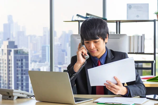 Asian Businessman Answering Customer Call Using Phone While Working Laptop — Fotografia de Stock