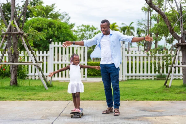 Feliz Padre Afroamericano Enseñar Hija Pequeña Jugar Skate Parque Público —  Fotos de Stock