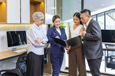 Farklı yaş grubundan Asyalı insanlardan oluşan bir ekip, genç liderle birlikte iş birliği ve iş konsepti için strateji yönetimi için veri ve bilgi analizi üzerine beyin fırtınası yapıyor.