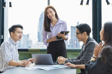 Genç Asyalı girişimci takımının, iş kurma ve eğitim için gökdelen görünümlü yeni proje pazarlama ve satış yönetimi için küçük bir takım toplantısı var