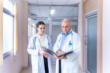 Doktorlardan oluşan bir ekip, deneyimli bir uzman doktorla, kesin bakım planı için hastanın tıbbi kayıtlarını tartışıyor ve beyin fırtınası yapıyor.