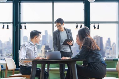 Genç Asyalı girişimci takımının, iş kurma ve eğitim için gökdelen görünümlü yeni proje pazarlama ve satış yönetimi için küçük bir takım toplantısı var