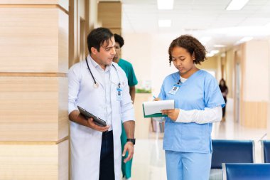 Çeşitlilik doktoru ve hemşire, deneyimli kıdemli hekim uzman doktorla, tam bakım planı üzerine, hastanın tıbbi kayıtlarını tartışıyor ve beyin fırtınası yapıyor.