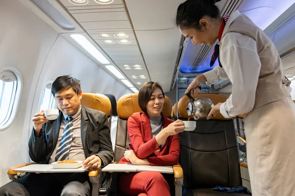 Flight attendant is serving coffee to the customer for in flight meal, airline travel and transportation usage