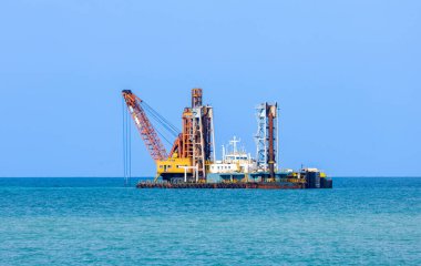 Kazıcı gemi kıyı şeridindeki deniz habitatını yok ederken büyük gemi taşımacılığında su seviyesini korumak için kıyı şeridinde çamur kovalıyor.