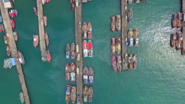 Vista aérea del muelle de pescadores que tiene muchos buques pesqueros anclando para el transporte de mariscos y suministros tierra adentro — Vídeo de stock