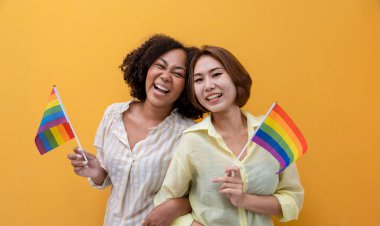 Sarı arka planda eşcinsellik ve ayrımcılık kullanımı eşitliği ve farklılıklarını yaymak için LGBTQ gökkuşağı bayrağı taşıyan bir çift aynı cinsiyet evliliği