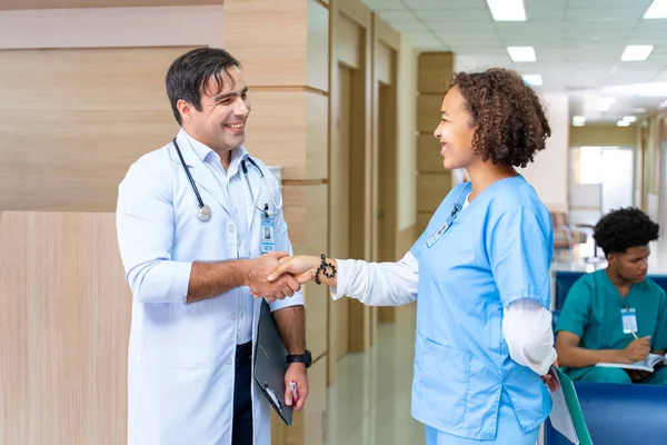Team of diversity doctor and nurse is handshaking after working on patient medical record for precise care plan with experienced senior physician specialist concept