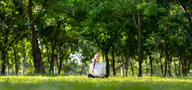 Ormanda rahatça meditasyon yapan bir kadın sağlıklı akıl ve ruh için güneş ışığıyla iç huzuru ve bilgeliği elde etmek için iç huzuru elde eder.