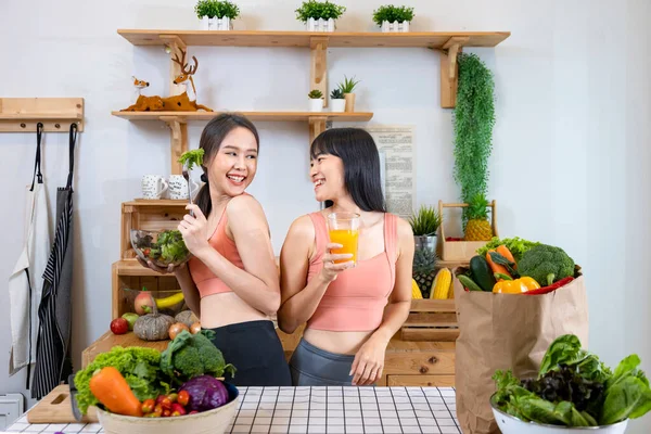 Asian sister is having a healthy food and drink while helping each other cooking in kitchen for vegan, vegetarian and plant based ingredient