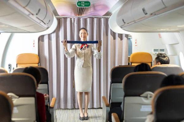 Asian flight attendant is demonstrating safety procedure using seat belt before taking off in the airplane for cabin crew and airline business