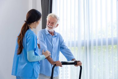 Hospice nurse is supporting Caucasian man to walk using treadmill in pension retirement center for home care rehabilitation and post recovery process