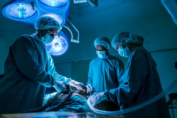 Team of surgeon doctor using defibrillator to give electrical shock to patient heart who is suffering from cardiac arrest in emergency surgical room for healthcare