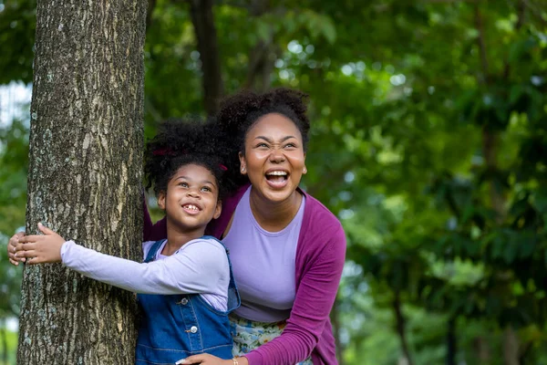 アフリカ系アメリカ人の母親は彼女の若い娘と一緒に遊んでいますが 公共の公園で夏のピクニックをしています — ストック写真