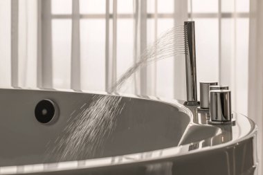 Geniş banyo borusundan akan suyu sıcak bir jakuziye dökün.