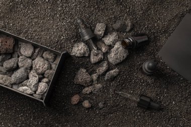 Aromaterapi için temel yağ ve volkanik taşlarla birlikte siyah kum arka planındaki demir metal kutuda bulunan mineral dağıtıcı. Aromaterapi, spa, güzellik tedavisi ve sağlık konsepti.