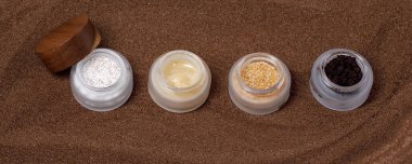 Kahverengi şeker, kahve ve bal karışımları kahverengi kum arka planında ev yapımı kozmetik için ahşap kapaklı cam kavanozlarda ovalanır. Güzellik, kaplıca, cilt bakımı, sıfır atık ambalaj konsepti