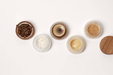 Esmer şeker, kahve ve bal malzemesi arka planda ev yapımı kozmetik için ahşap kapaklı cam kavanozlarda ovalanır. Güzellik, kaplıca, cilt bakımı, sıfır atık ambalaj konsepti