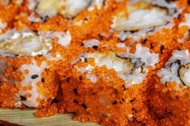 Suşi California 'yı kar yengeci, krem peynir, salatalık, susam tohumu ve masago havyar makrosu ile kaplıyor.