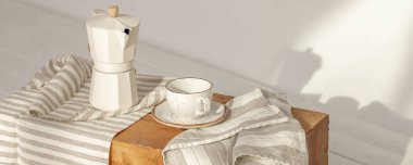 İtalyan kahve makinesi, ahşap saplı ve beyaz kahve fincanı, katı ahşap damgalı. Güneş ışığında kremalı havlularla süslenmiş. Duvarda güzel gölgeler yaratıyor.