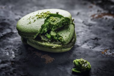 Makro, gri kil zemin üzerinde yeşil parçalanmış badem kurabiyesi.