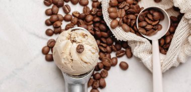 Bir kepçe kahve ve beyaz kil arka planda kavrulmuş kahve çekirdekleri.