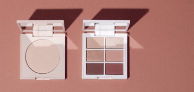 Göz farı paleti ve pembe arkaplanda parlak toz. Kozmetik ürün arkaplanı