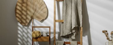 Organik el yapımı sabun, deniz süngeri, ahşap merdivende asılı keten havlular, bej sabun spreyi, deri yüzen vücut kayışı ve desenli vazoda kurumuş haşhaş çiçekleri. Sıfır atık banyo aksesuarı