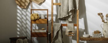 Organik el yapımı sabun, deniz süngeri, ahşap merdivende asılı keten havlular, bej sabun spreyi, deri yüzen vücut kayışı ve desenli vazoda kurumuş haşhaş çiçekleri. Sıfır atık banyo aksesuarı