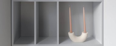 Geometrik mumlarla minimalist tasarım içerisindeki açık gri kitaplık