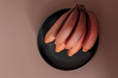 Bej masada bir sürü olgun organik kırmızı muz. Meyve arkaplanı. Musa acuminata Red Dacca. Daha fazla Beta karoten ve C vitamini içerir.