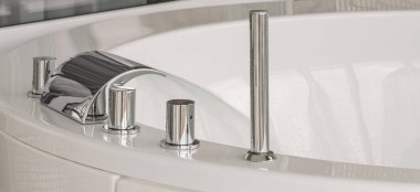 Su lüks ve modern bir musluktan büyük ve modern bir küvete akar. Spa, rahatlama, hijyen konsepti